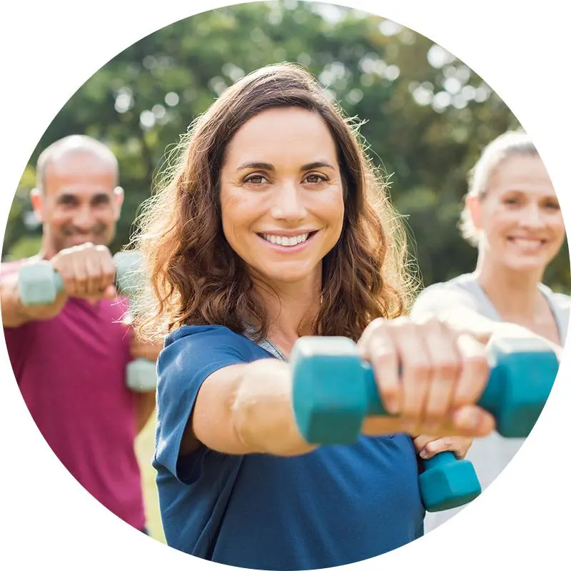 Woman lifting weights outdoors with friends.
